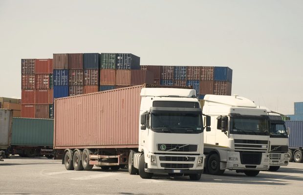 Ciężarówki przed stertą kontenerów w centrum logistycznym